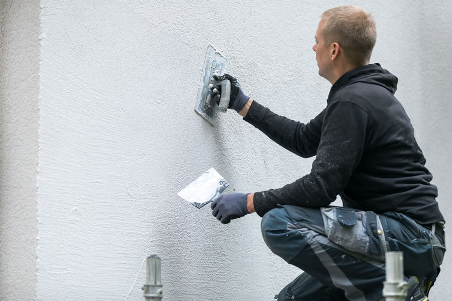 A workman applying render to a wall