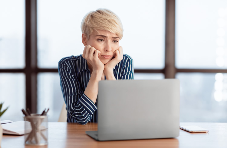 A woman looking sad while staring at a computer screen