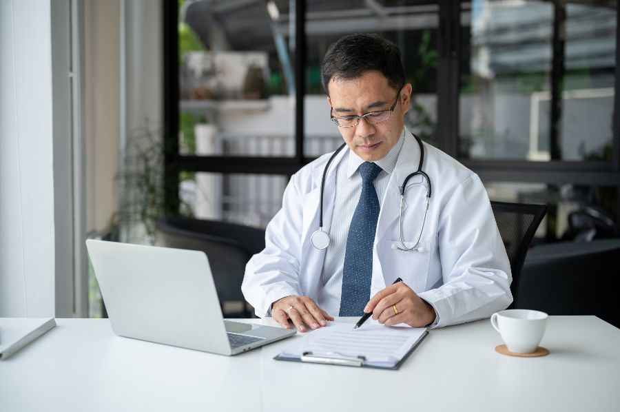 A doctor with a laptop making notes